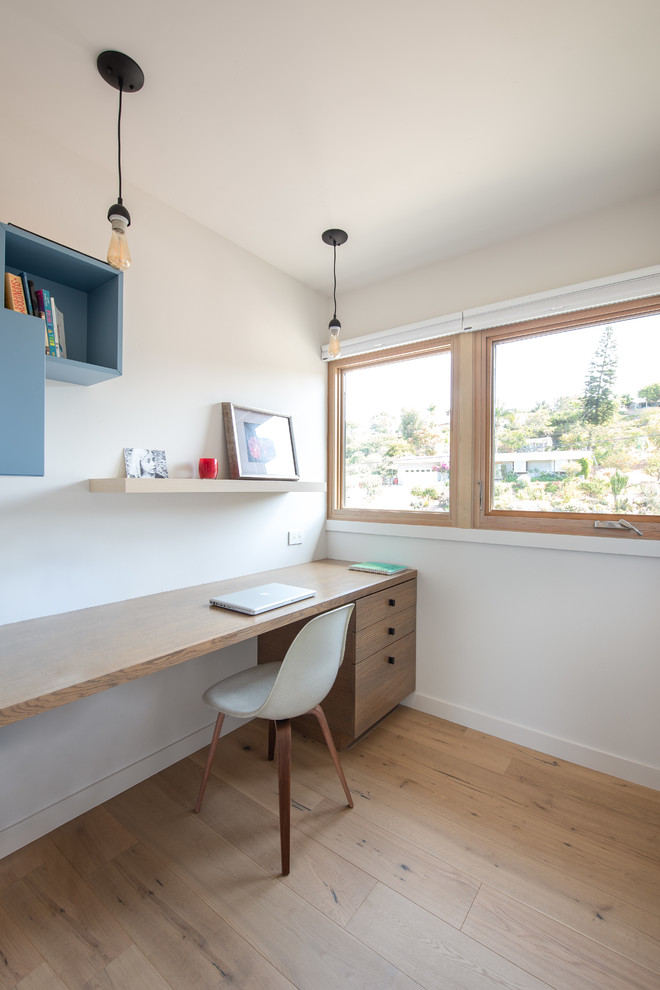 Modernes Arbeitszimmer ohne Kamin mit weißer Wandfarbe, hellem Holzboden und Einbau-Schreibtisch in San Diego