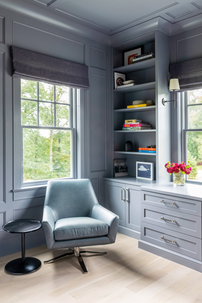 Modelo de despacho clásico de tamaño medio sin chimenea con paredes grises, suelo de madera clara, escritorio empotrado y suelo marrón