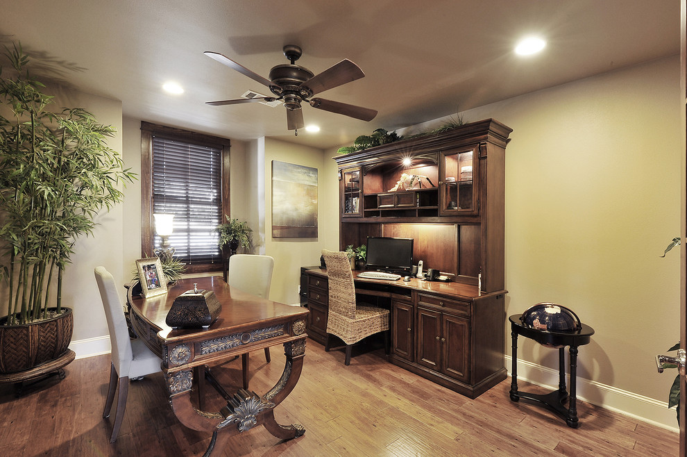 Immagine di uno studio tradizionale con pareti beige, pavimento in legno massello medio e scrivania autoportante
