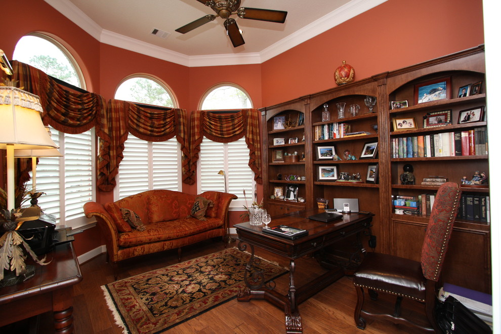 Idéer för stora vintage hemmabibliotek, med mellanmörkt trägolv, ett fristående skrivbord och orange väggar