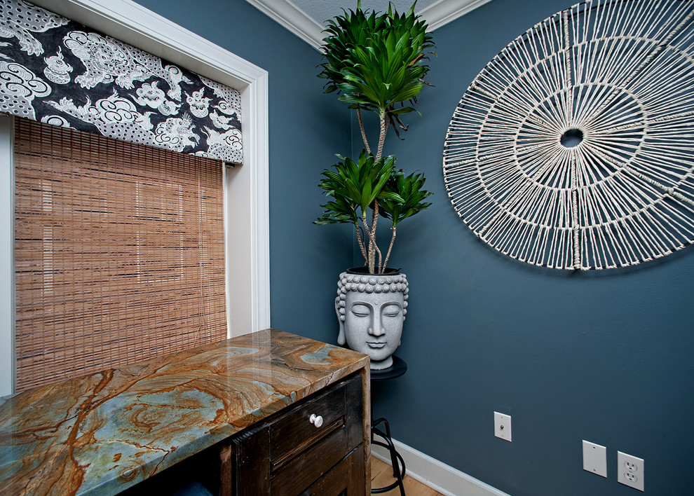 Ejemplo de despacho bohemio pequeño con paredes azules, suelo de madera clara y escritorio empotrado