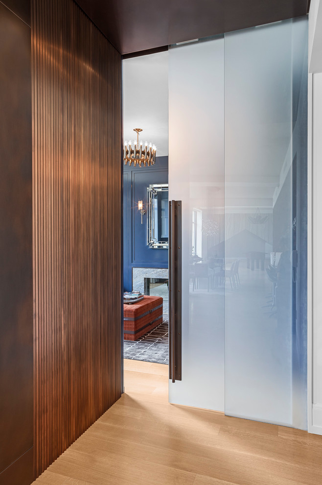 Modelo de despacho minimalista con paredes azules, chimenea de doble cara, marco de chimenea de piedra y escritorio empotrado