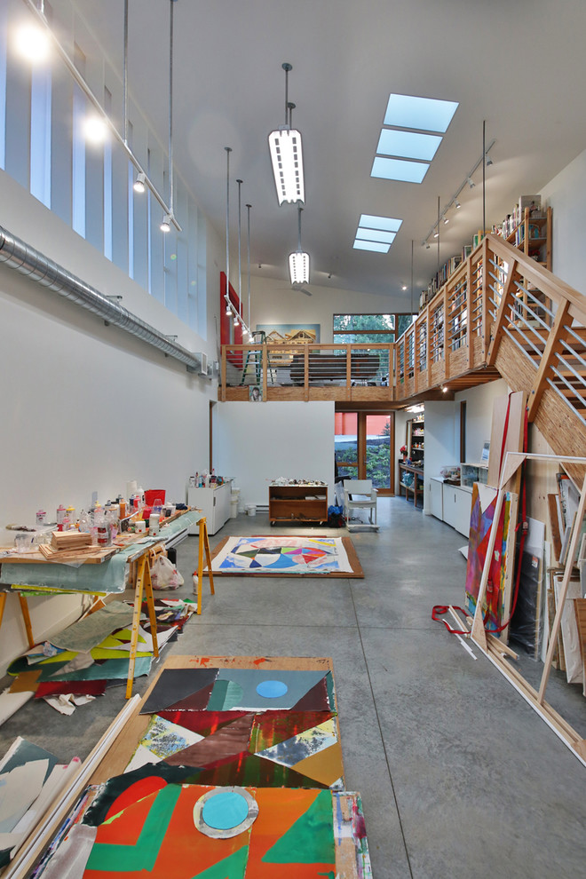 Cette image montre un bureau urbain de type studio avec un mur blanc, sol en béton ciré, un bureau intégré et un sol gris.