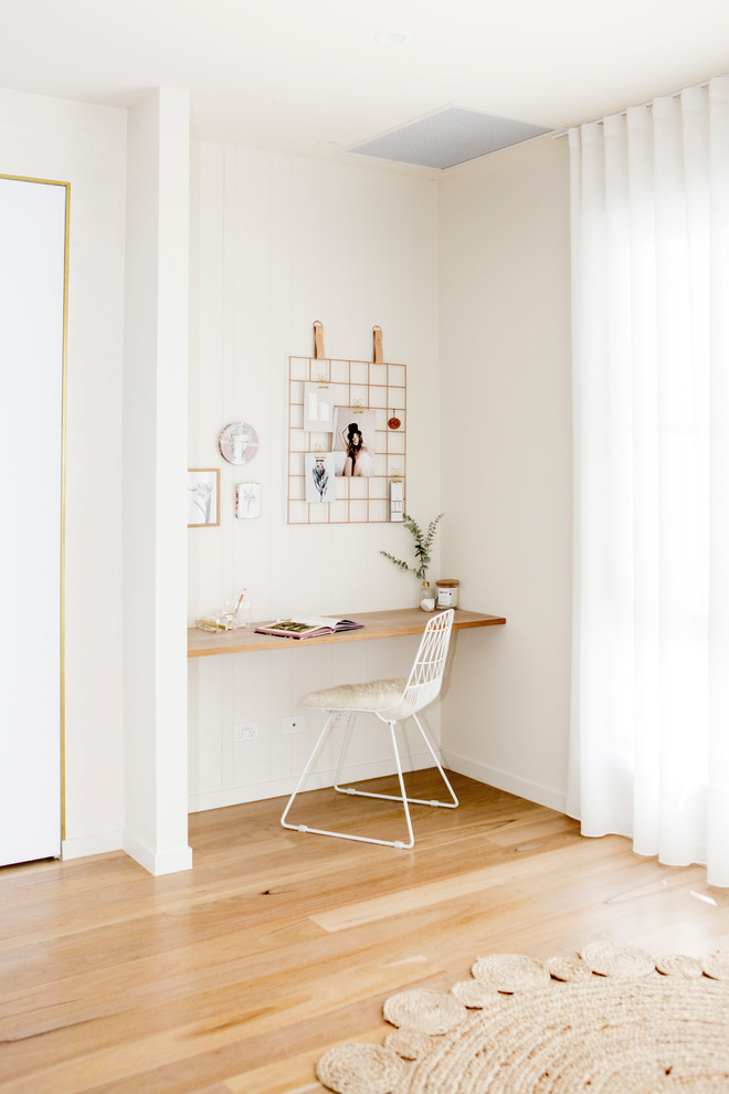 Стильный дизайн: кабинет в скандинавском стиле с белыми стенами, паркетным полом среднего тона, встроенным рабочим столом и коричневым полом - последний тренд