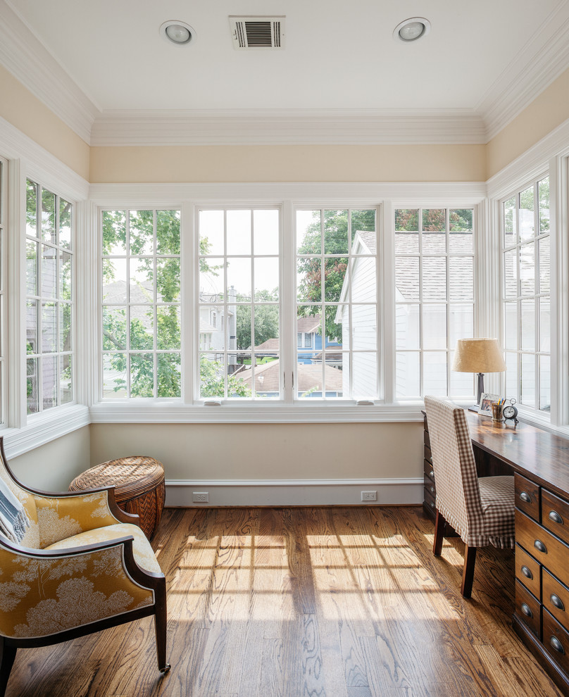 Immagine di un ampio studio classico con pavimento in legno massello medio, scrivania autoportante, pareti beige e pavimento marrone