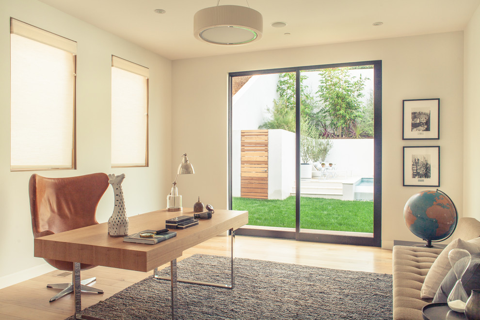 Cette image montre un bureau design avec un mur blanc, un sol en bois brun et un bureau indépendant.