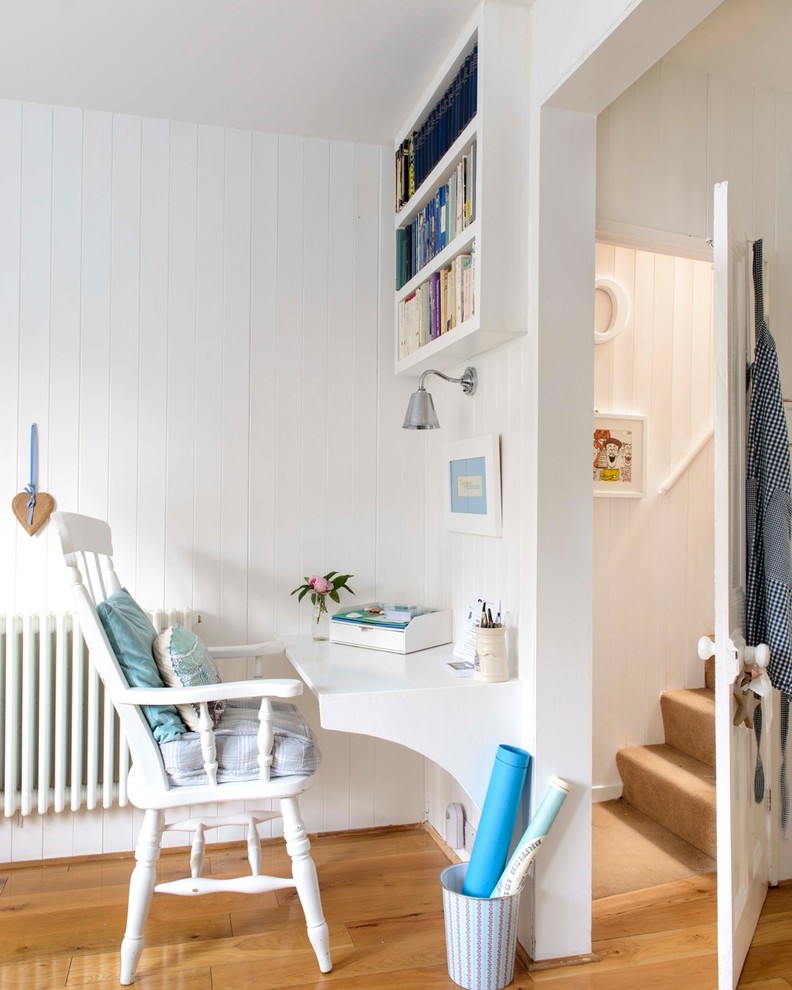 Home office - small coastal built-in desk medium tone wood floor home office idea in Kent with white walls