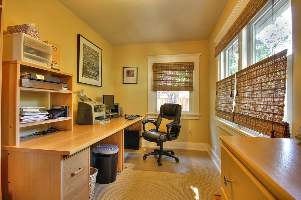 Foto på ett litet amerikanskt arbetsrum, med gula väggar, heltäckningsmatta och ett fristående skrivbord