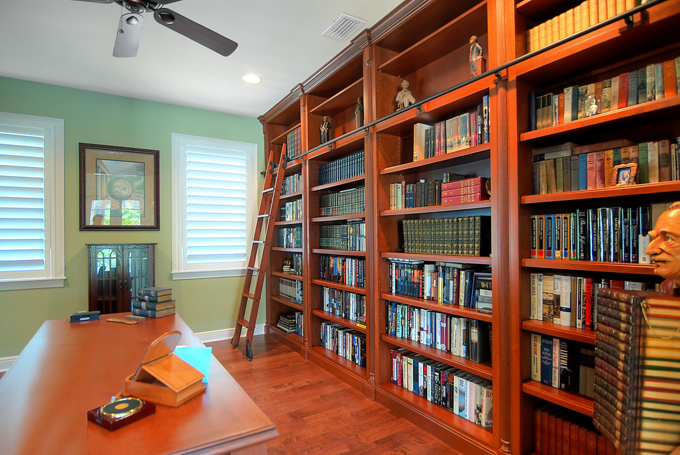 Inspiration för ett stort vintage arbetsrum, med ett fristående skrivbord, ett bibliotek, mellanmörkt trägolv, brunt golv och gröna väggar