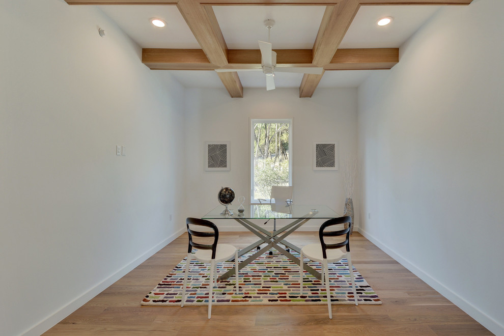 Modernes Arbeitszimmer mit Arbeitsplatz, weißer Wandfarbe, hellem Holzboden und freistehendem Schreibtisch in Austin