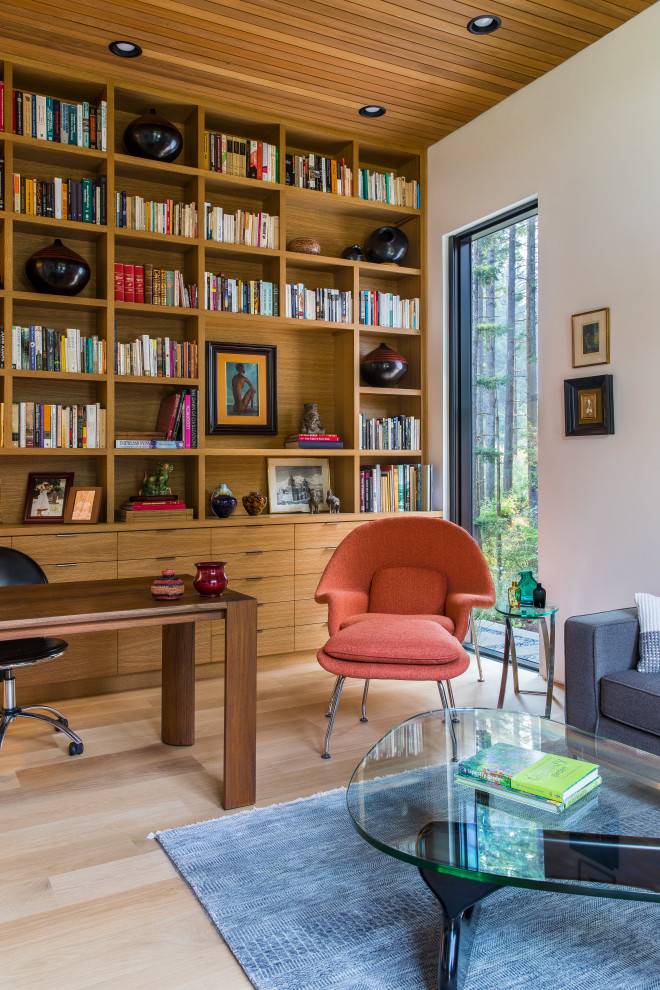 Inspiration för mellanstora moderna hemmabibliotek, med vita väggar, ljust trägolv och ett fristående skrivbord