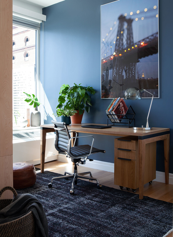 Идея дизайна: рабочее место в стиле лофт с синими стенами, отдельно стоящим рабочим столом и светлым паркетным полом без камина