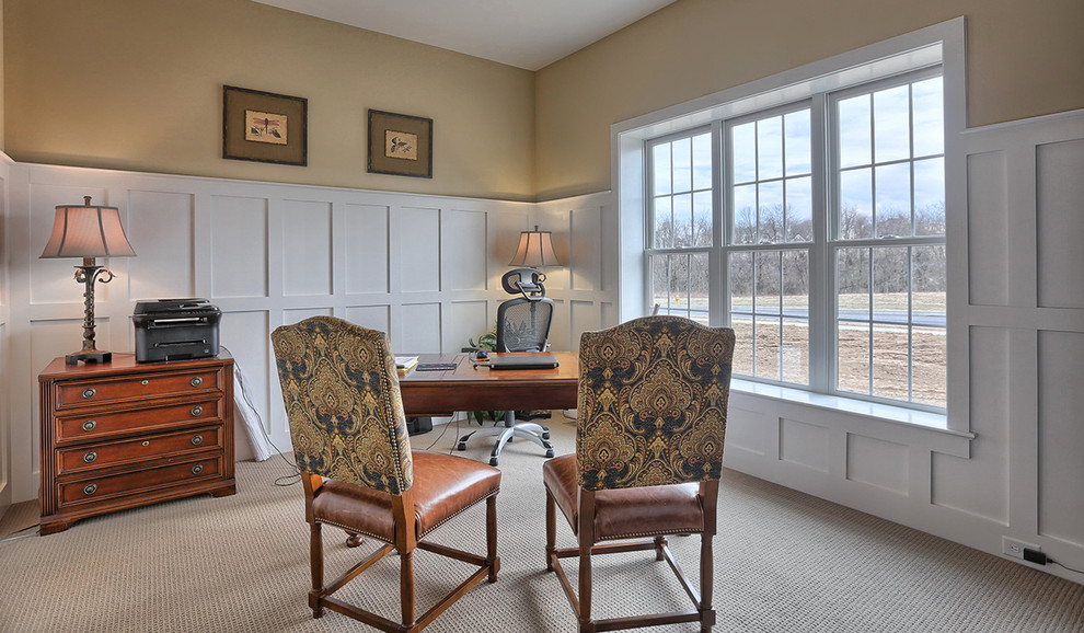 Großes Klassisches Arbeitszimmer ohne Kamin mit Arbeitsplatz, beiger Wandfarbe, Teppichboden und freistehendem Schreibtisch in Sonstige