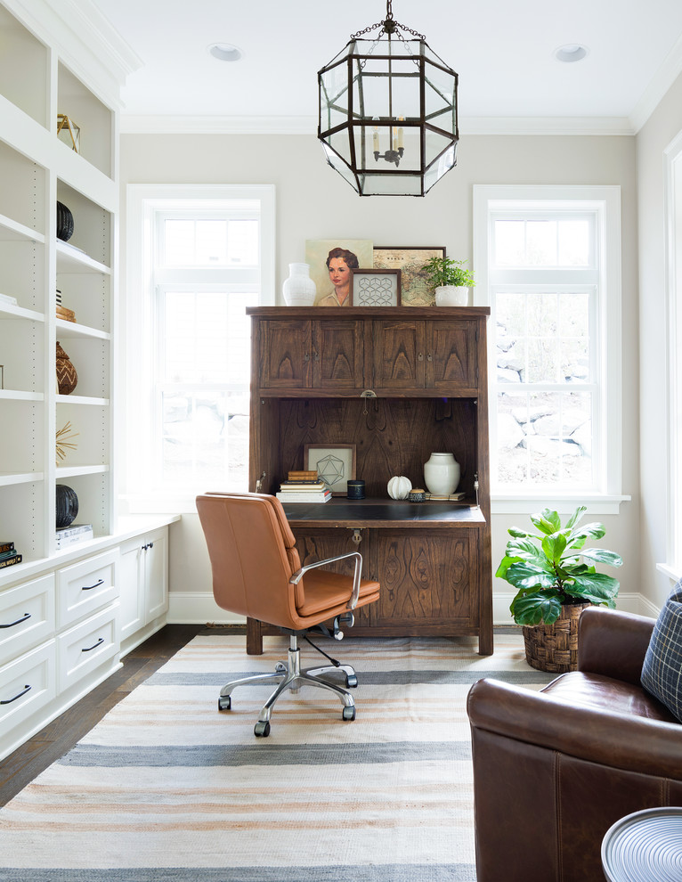 This is an example of a classic study in Minneapolis with beige walls, dark hardwood flooring, no fireplace and a freestanding desk.