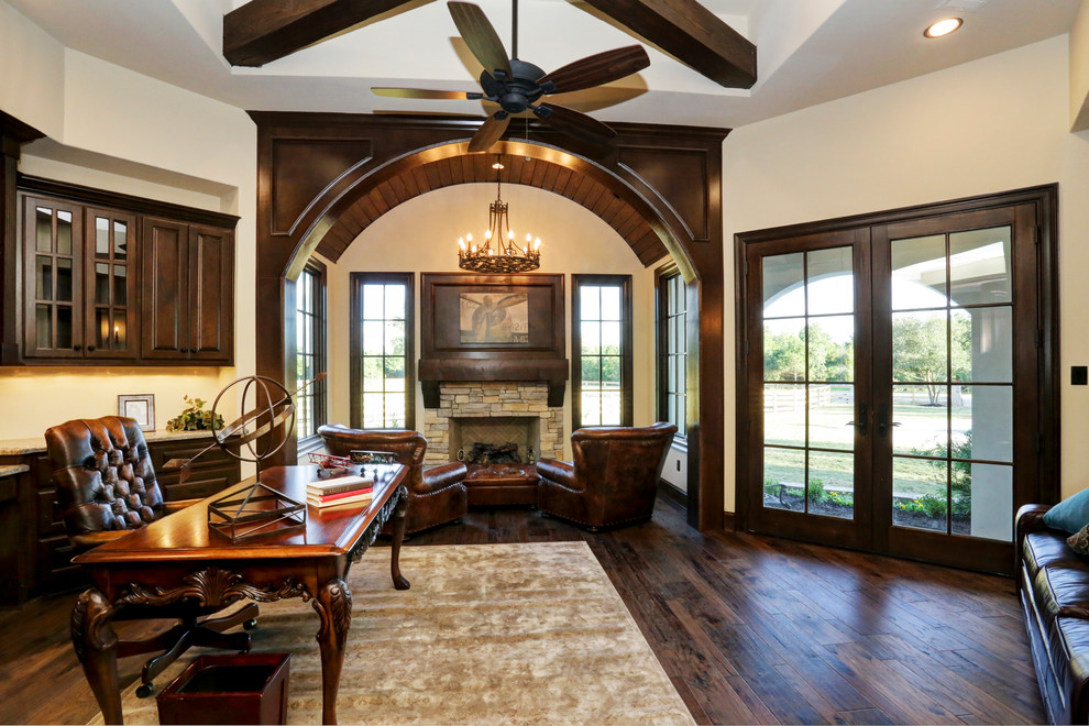 Example of a large classic freestanding desk dark wood floor study room design in Houston with white walls, a standard fireplace and a stone fireplace
