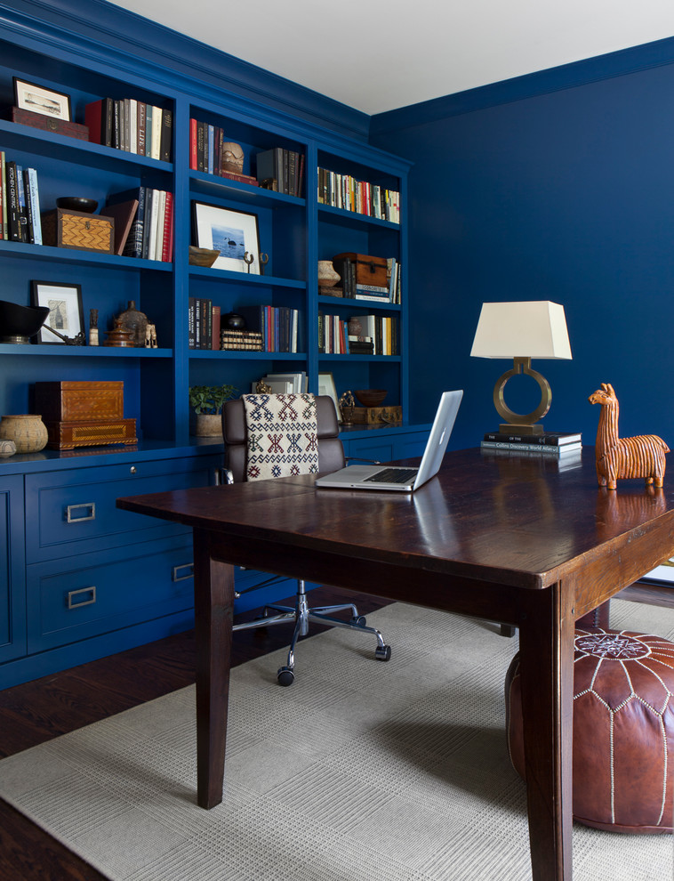 На фото: рабочее место в стиле неоклассика (современная классика) с синими стенами, темным паркетным полом и отдельно стоящим рабочим столом с