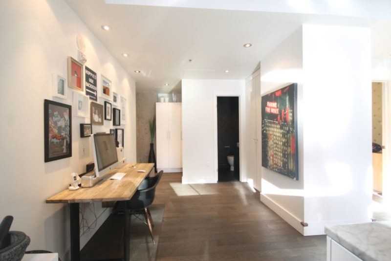 Cette image montre un petit bureau urbain avec un mur blanc, parquet foncé, un bureau indépendant et un sol marron.