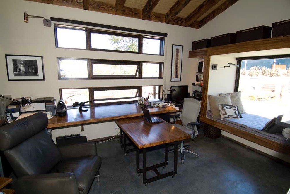 Modelo de despacho de estilo zen de tamaño medio con paredes beige, suelo de cemento y escritorio independiente