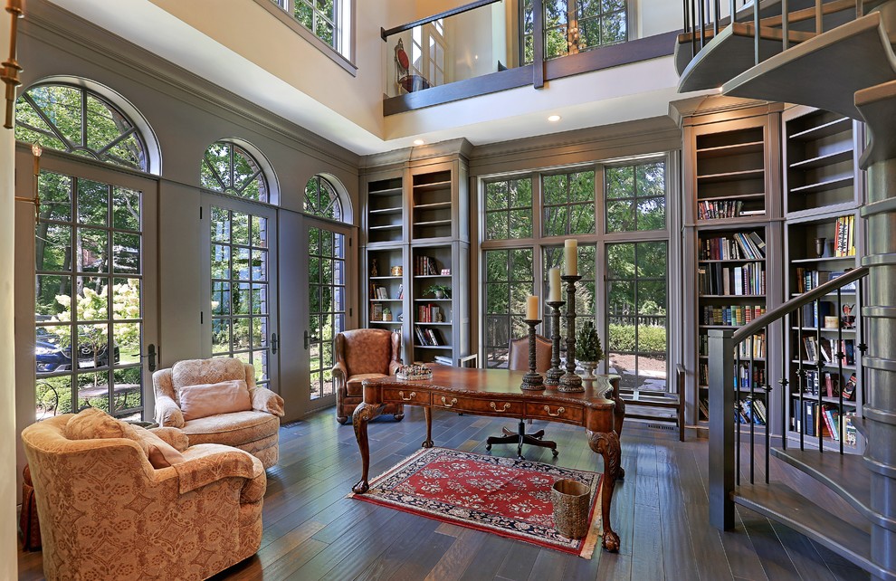 Idéer för ett stort klassiskt hemmabibliotek, med grå väggar, mellanmörkt trägolv, ett fristående skrivbord och brunt golv