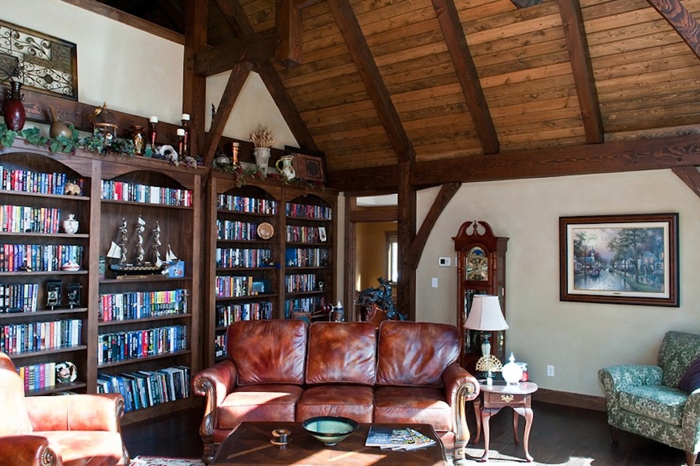 Immagine di un grande studio american style con libreria, pareti bianche, parquet scuro e pavimento marrone