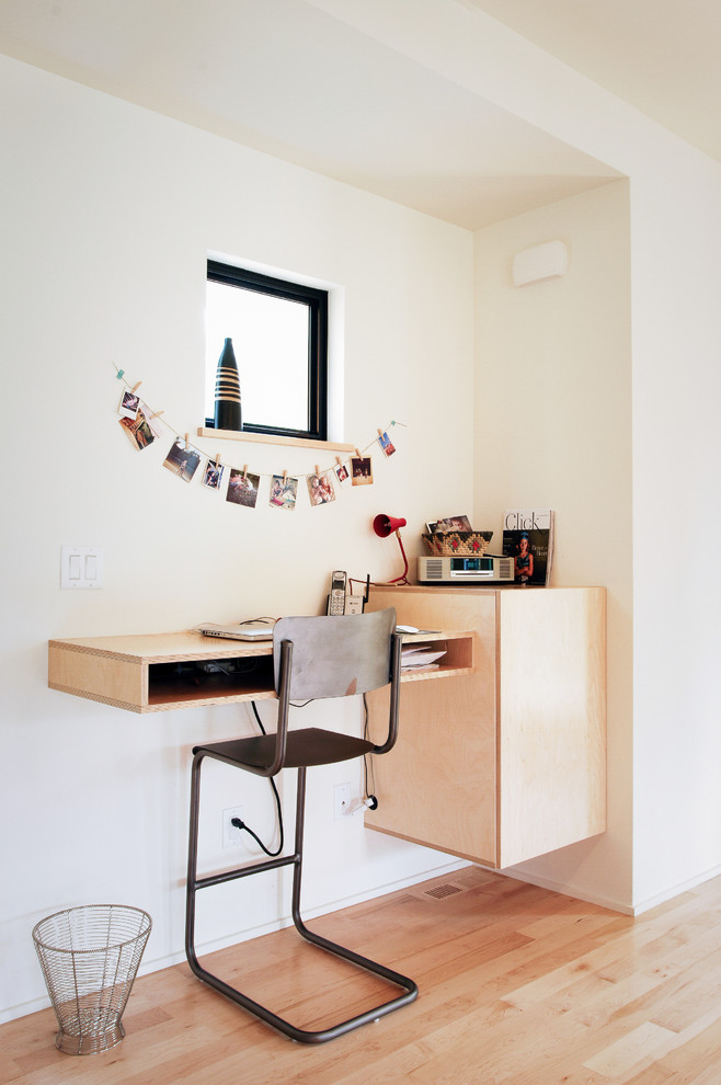 Modelo de despacho contemporáneo pequeño con paredes blancas, suelo de madera clara y escritorio empotrado