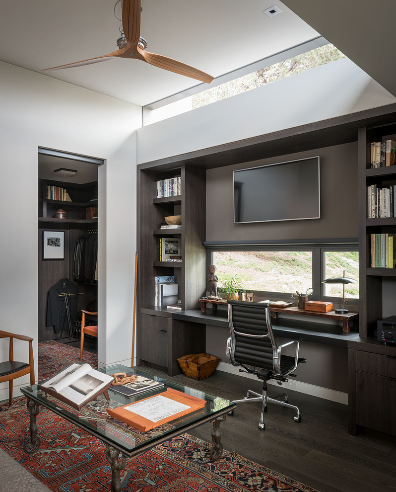 Exemple d'un bureau rétro avec une bibliothèque ou un coin lecture, un mur blanc, parquet foncé, aucune cheminée et un bureau intégré.