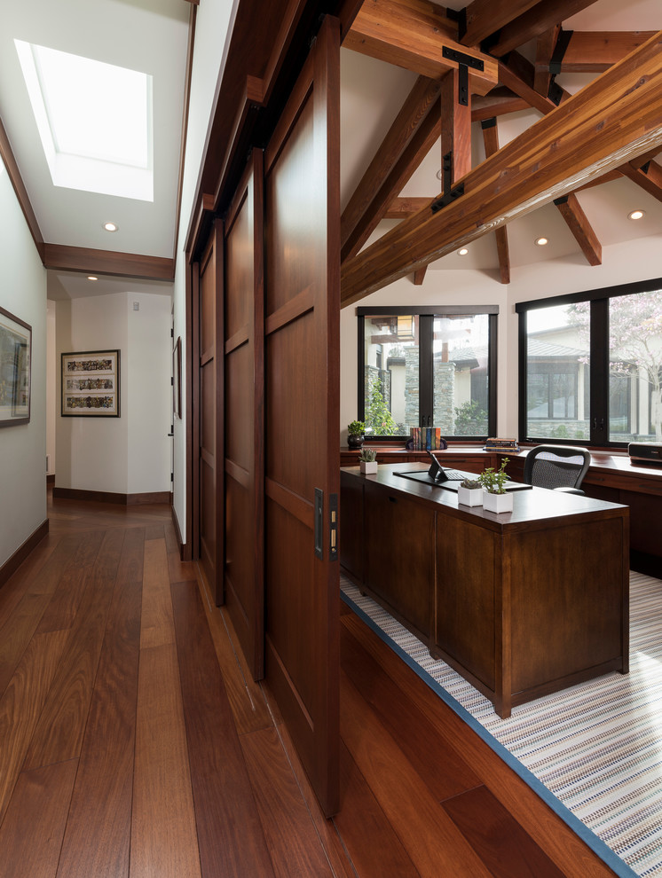 Ejemplo de despacho moderno extra grande sin chimenea con paredes blancas, suelo de madera en tonos medios, escritorio empotrado y suelo marrón