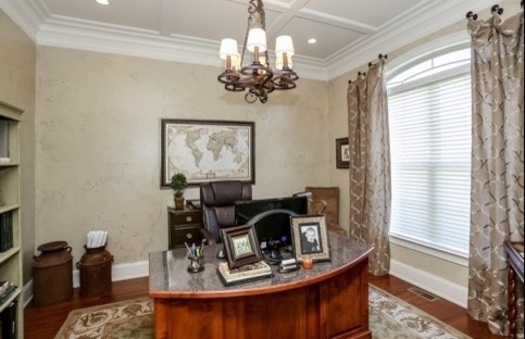 Foto de despacho tradicional de tamaño medio sin chimenea con paredes beige, suelo de madera oscura y escritorio independiente