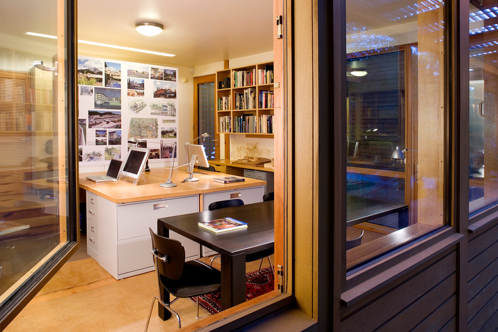 Immagine di un piccolo atelier moderno con pareti bianche, pavimento in cemento e scrivania incassata
