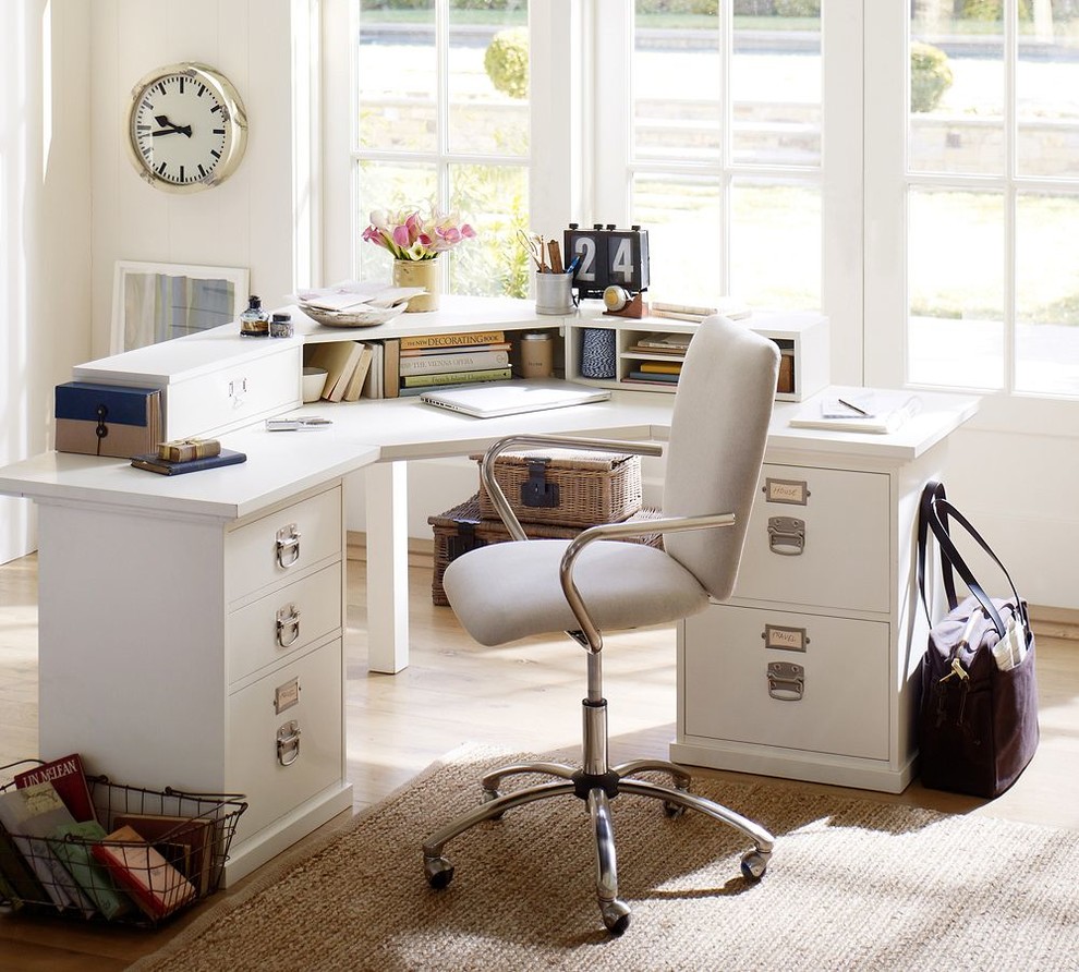 Klassisk inredning av ett mellanstort arbetsrum, med vita väggar, mellanmörkt trägolv och ett fristående skrivbord