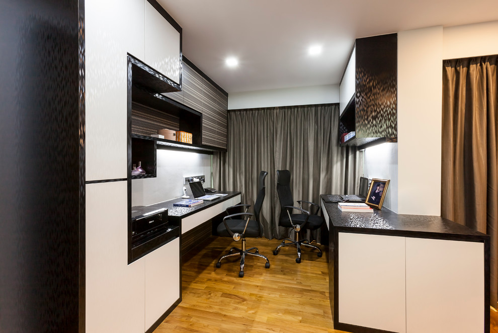 This is an example of a medium sized contemporary study in Singapore with white walls, light hardwood flooring and a built-in desk.