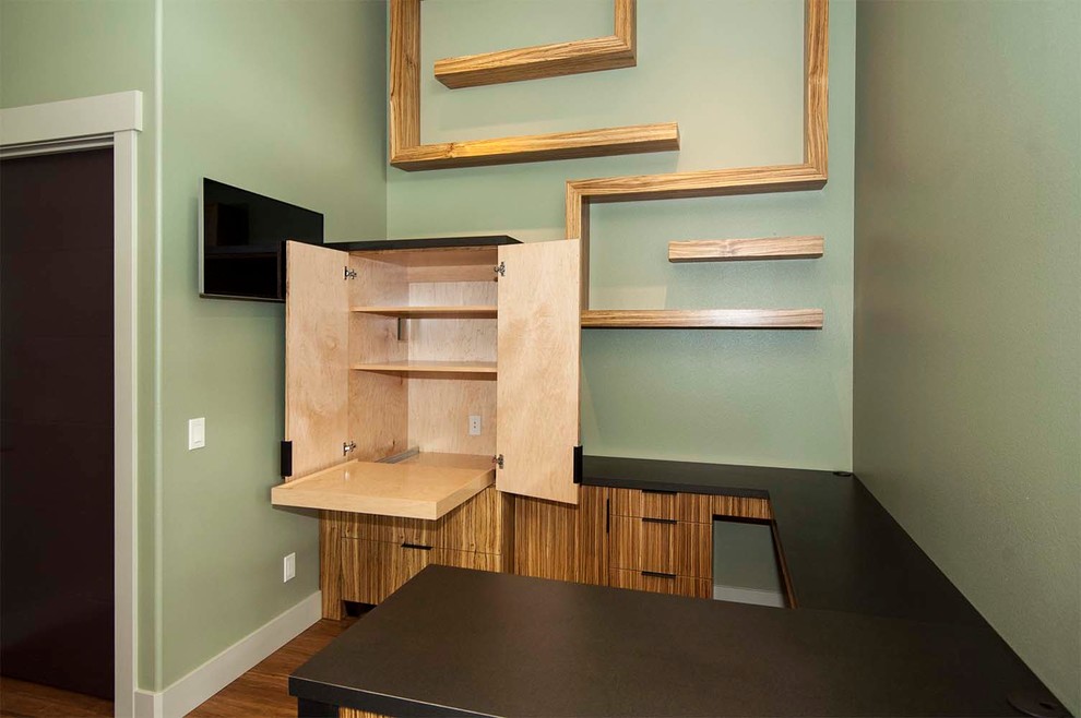 Mittelgroßes Arbeitszimmer mit Arbeitsplatz, grüner Wandfarbe, braunem Holzboden und freistehendem Schreibtisch in Sonstige