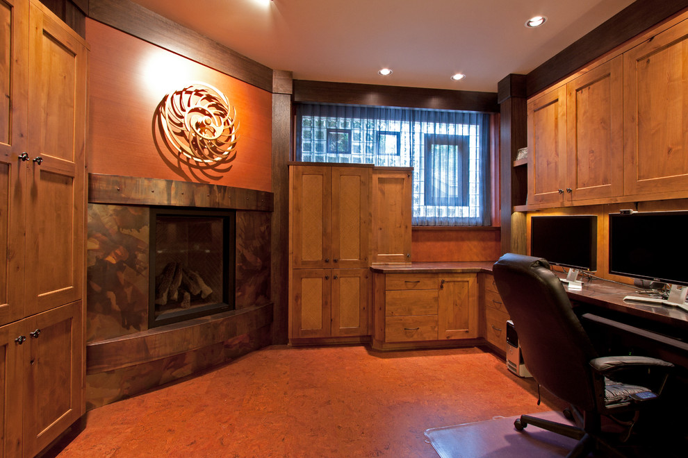 На фото: кабинет в восточном стиле с пробковым полом, угловым камином, фасадом камина из металла и встроенным рабочим столом
