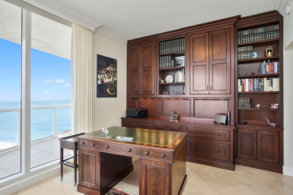 Diseño de despacho de estilo americano de tamaño medio con paredes beige, suelo de travertino, escritorio independiente y suelo beige