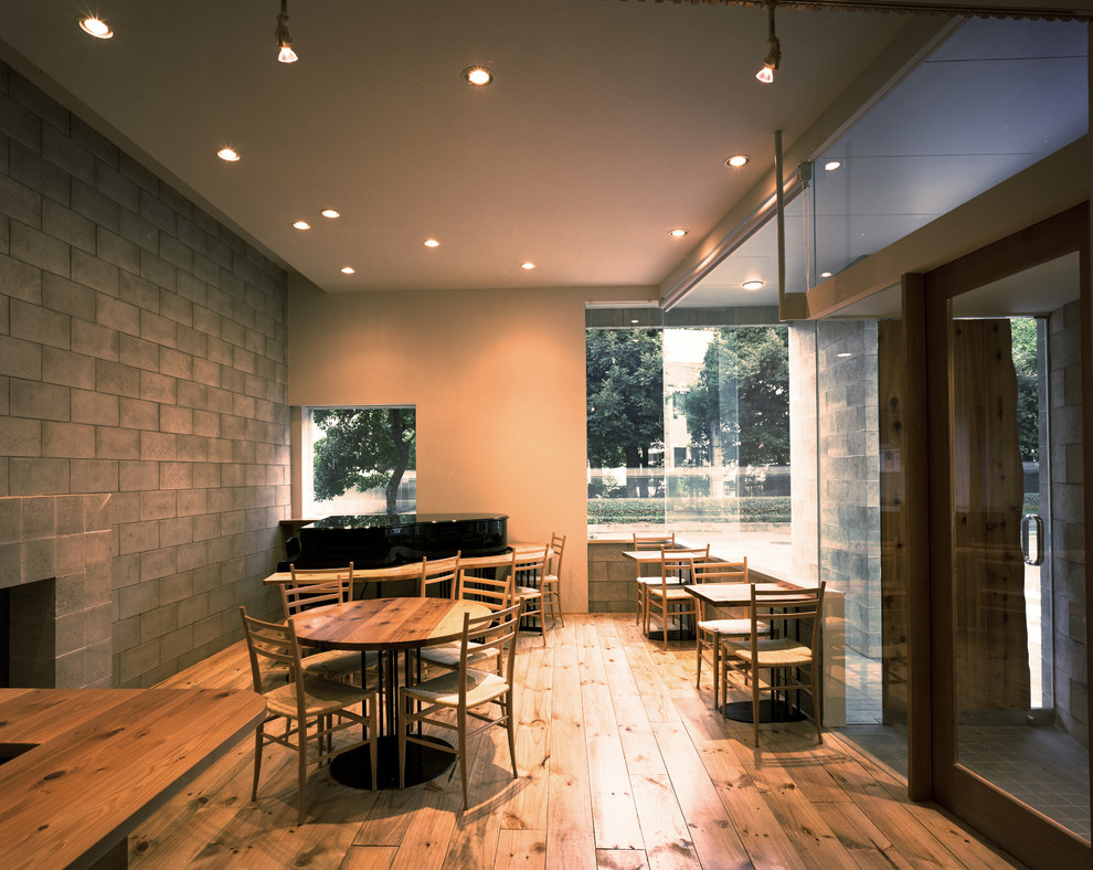 Esempio di un atelier minimalista di medie dimensioni con pareti grigie, pavimento in legno massello medio, nessun camino, cornice del camino in intonaco, scrivania incassata e pavimento marrone