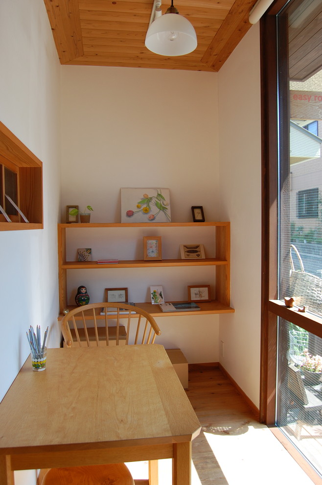Bild på ett litet orientaliskt arbetsrum, med vita väggar, ljust trägolv och ett fristående skrivbord