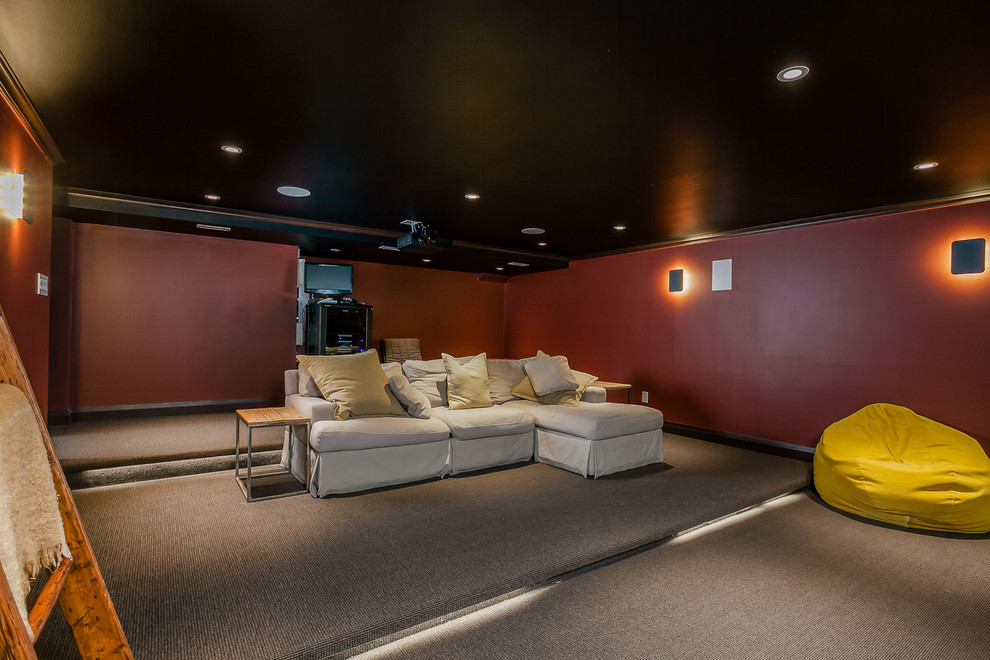 Cette photo montre une salle de cinéma tendance de taille moyenne et fermée avec un mur rouge, moquette, un écran de projection et un sol gris.