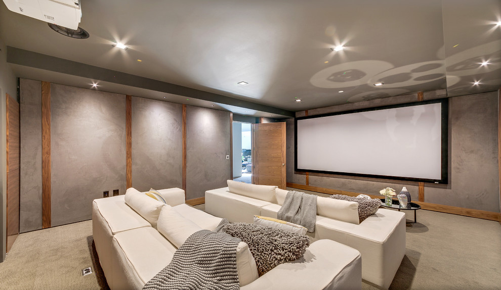 Пример оригинального дизайна: изолированный домашний кинотеатр в современном стиле с серыми стенами, ковровым покрытием, проектором и серым полом