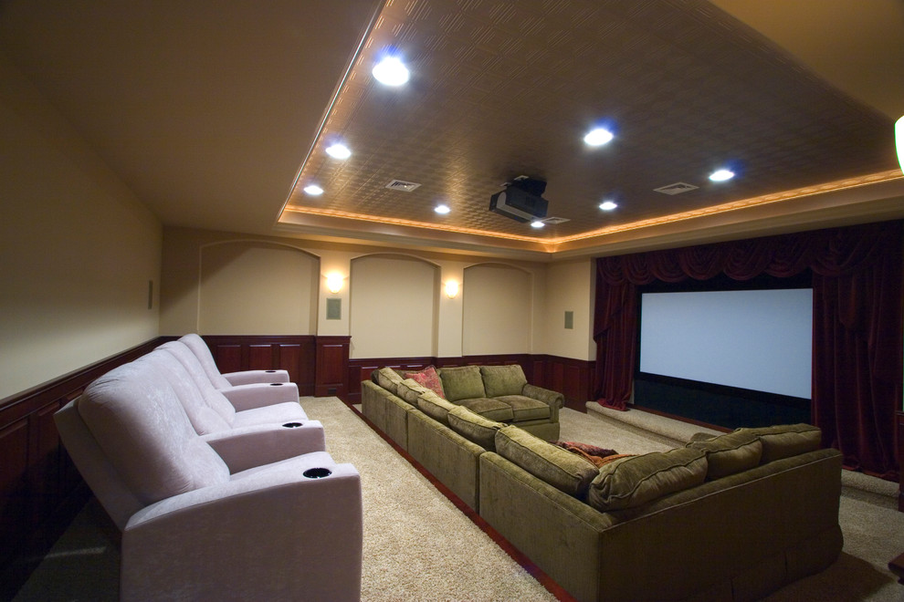 Стильный дизайн: огромный изолированный домашний кинотеатр в классическом стиле с бежевыми стенами, ковровым покрытием и проектором - последний тренд