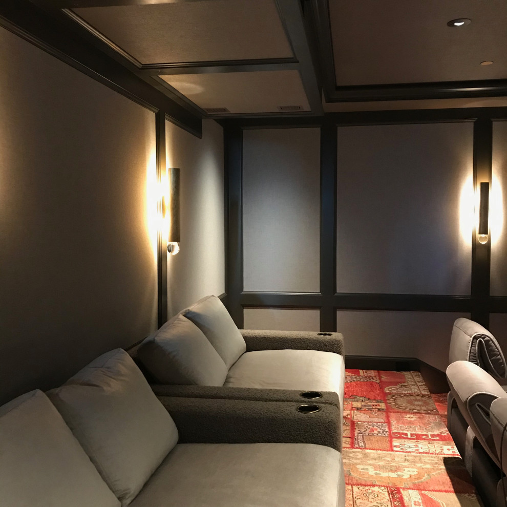 Aménagement d'une grande salle de cinéma contemporaine fermée avec un mur beige, moquette, un écran de projection et un sol multicolore.