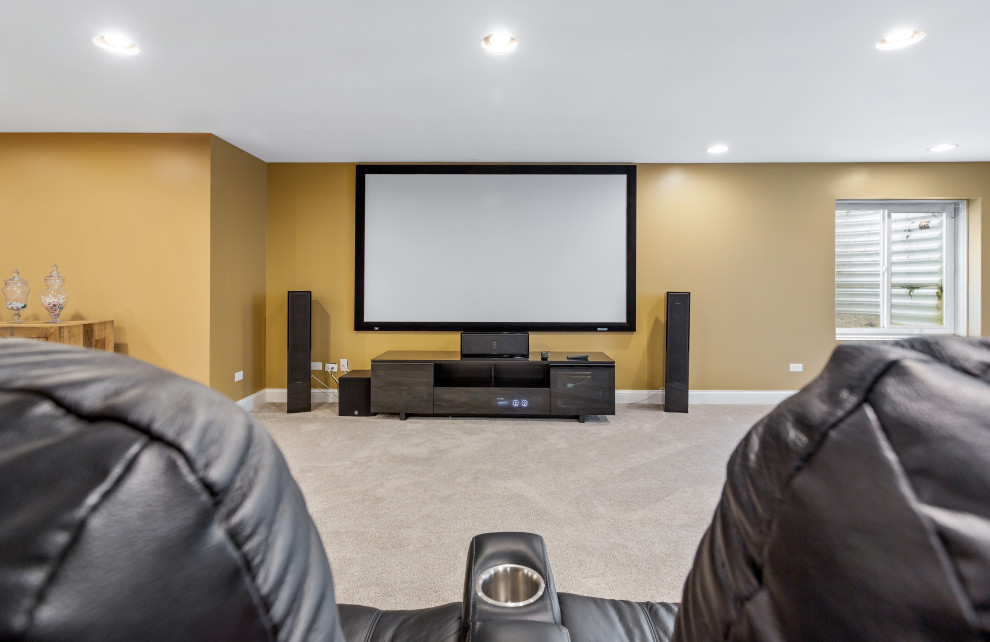 Inspiration for a large contemporary enclosed home cinema in Chicago with beige walls, carpet and a projector screen.