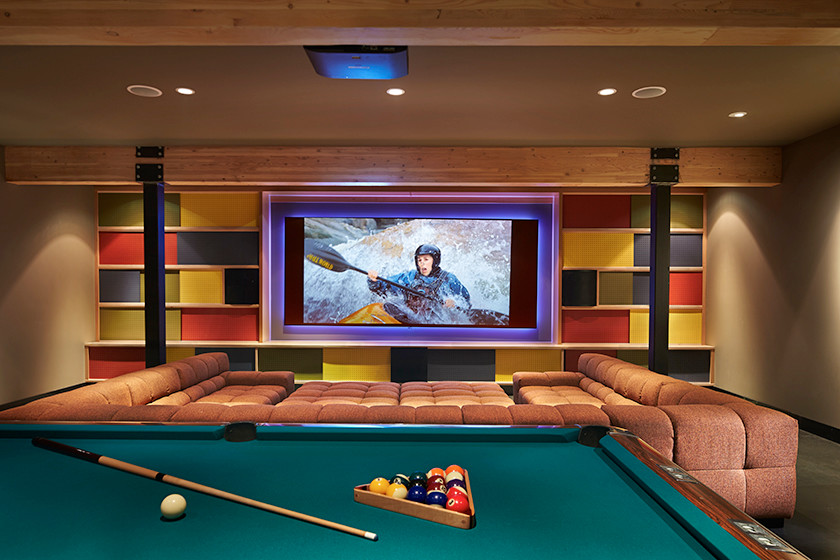 Immagine di un ampio home theatre moderno chiuso con pareti multicolore, pavimento in cemento e schermo di proiezione