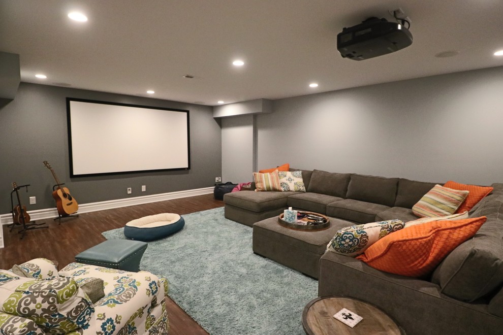 Foto de cine en casa cerrado tradicional renovado de tamaño medio con paredes grises, suelo de madera en tonos medios, pantalla de proyección y suelo marrón