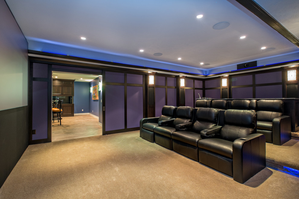 Imagen de cine en casa cerrado de estilo americano grande con paredes azules, moqueta y pantalla de proyección