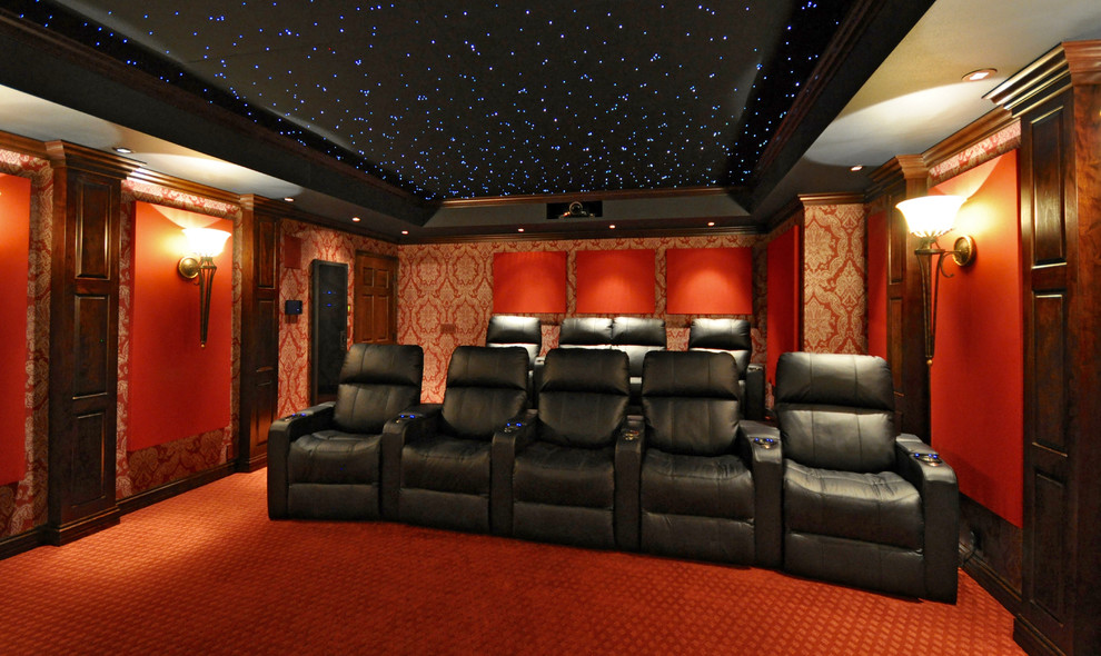 Cette photo montre une salle de cinéma chic de taille moyenne et fermée avec un mur rouge, moquette, un écran de projection et un sol orange.