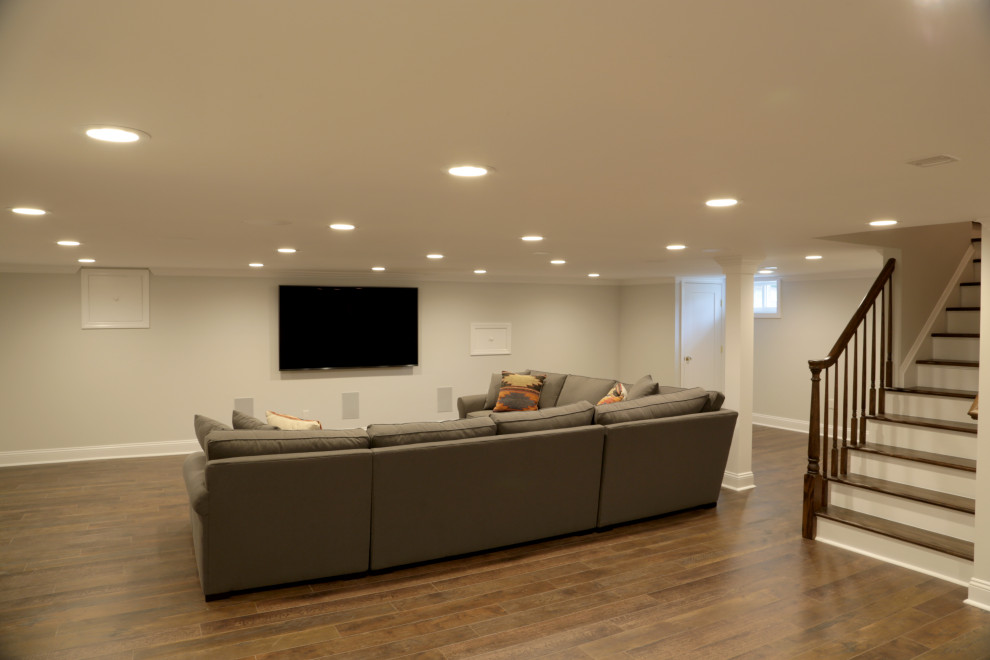 Large elegant laminate floor and brown floor home theater photo in New York with beige walls