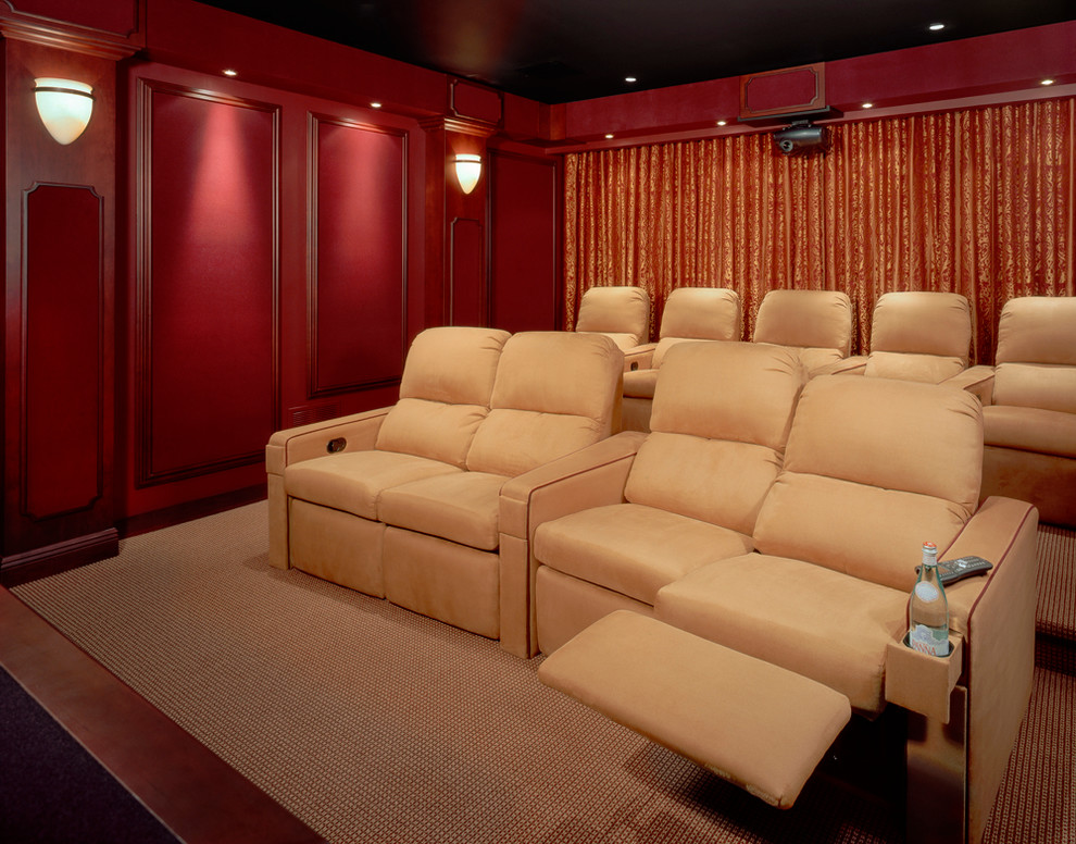 Cette image montre une grande salle de cinéma traditionnelle fermée avec un mur rouge, moquette, un écran de projection et un sol marron.