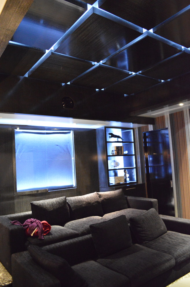 Immagine di un grande home theatre minimalista chiuso con pareti nere, moquette e schermo di proiezione