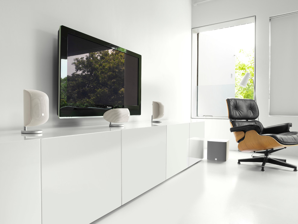 Modelo de cine en casa abierto moderno de tamaño medio con paredes blancas, suelo de madera oscura y televisor colgado en la pared