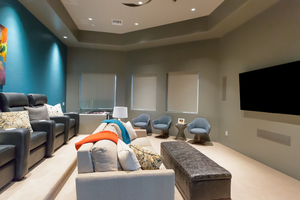 Modelo de cine en casa cerrado actual de tamaño medio con paredes grises, moqueta, televisor colgado en la pared y suelo beige